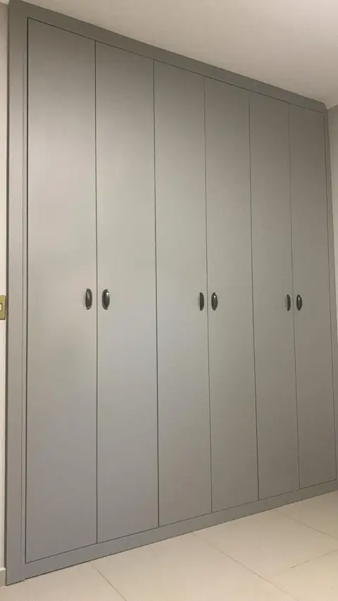 Guarda-roupa planejado de parede inteira com portas cinza e puxadores discretos